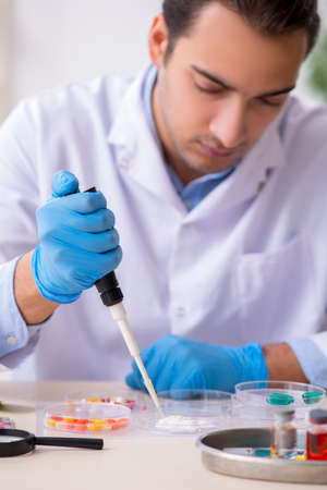 Young male lab assistant in drug synthesis concept