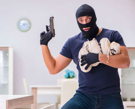 Robber wearing balaclava stealing valuable things