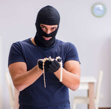 Robber wearing balaclava stealing valuable things