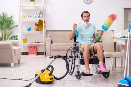Young man in wheel-chair cleaning the houseの写真素材