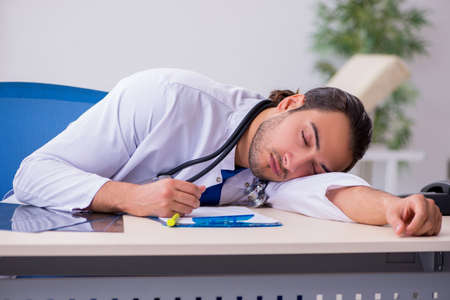 Young male doctor being tired after night shiftの写真素材