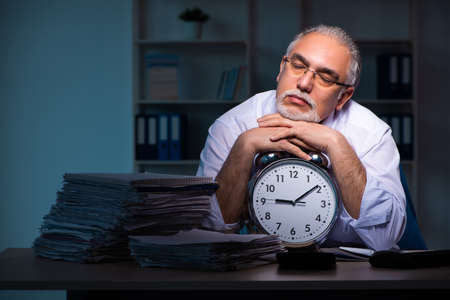 Old male employee working late in the office