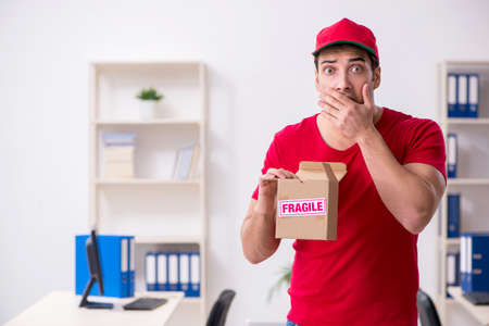 Young male courier delivering postbox to the office