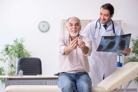 Young male doctor and old patient in antismoking conceptの写真素材