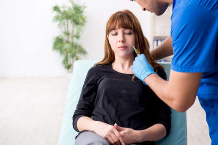 Young beautiful woman visiting doctor in plastic surgery conceptの写真素材