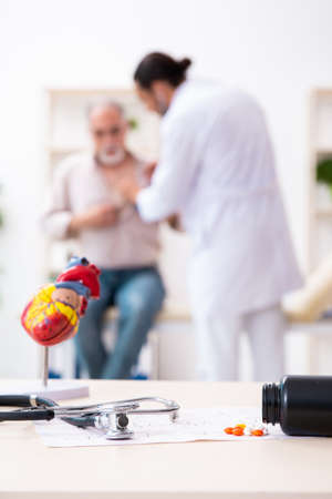 Old man visiting young male doctor cardiologistの写真素材