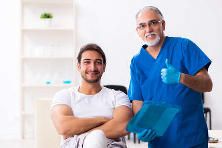 Leg injured man visiting old doctor in first aid conceptの写真素材