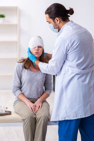 Young head injured woman visiting young male doctorの写真素材