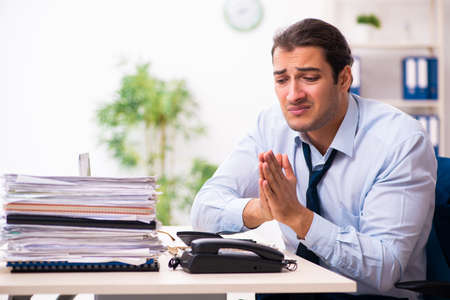 Young male employee unhappy with excessive workの写真素材