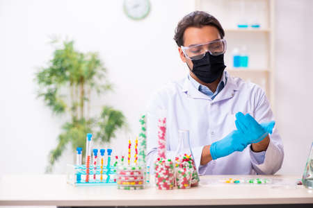 Young male chemist in drug synthesis concept