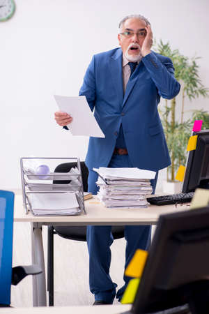 Old male employee and too much work in the officeの写真素材
