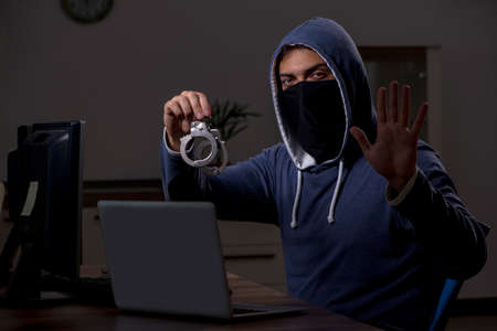 Male hacker hacking security firewall late in officeの写真素材