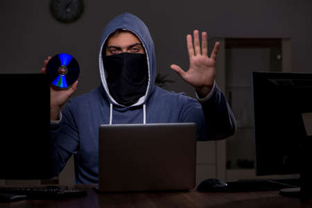 Male hacker hacking security firewall late in officeの写真素材