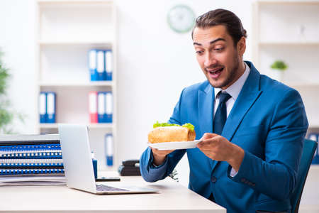 Young male employee having breakfast at workplaceの写真素材