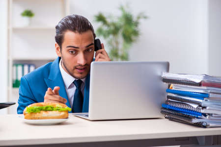 Young male employee having breakfast at workplaceの写真素材