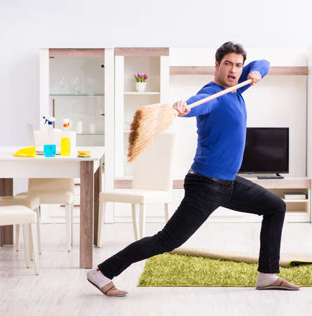 Young man cleaning floor with broom