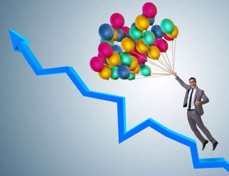 The businessman flying on balloons over graphの写真素材