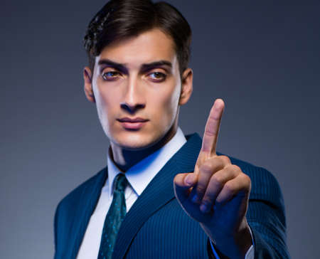Businessman pressing virtual buttons on gray backgroundの写真素材