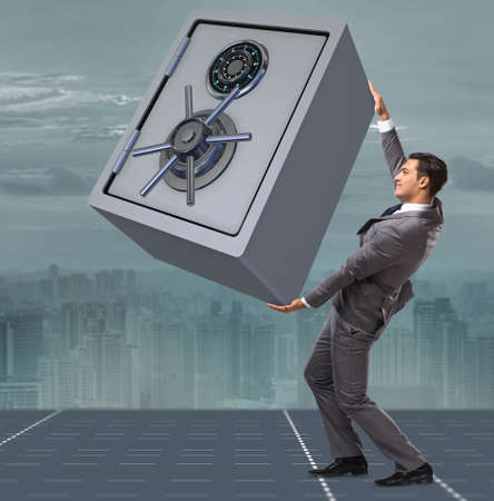 Businessman carrying metal safe in security conceptの写真素材