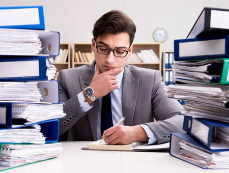 Busy businessman under stress due to excessive workの写真素材
