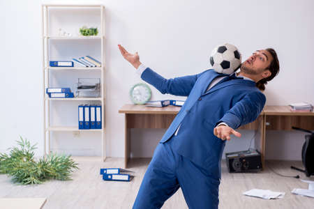 Young male employee playing football in the officeの写真素材
