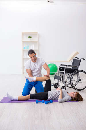 Leg injured woman doing sport exercises with personal coachの写真素材