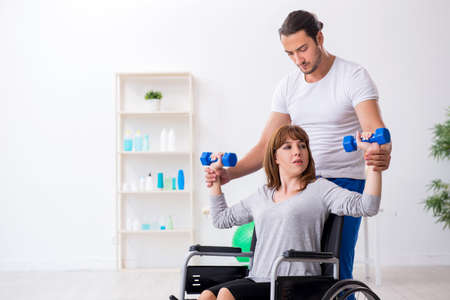 Woman in wheel-chair doing sport exercises with personal coachの写真素材