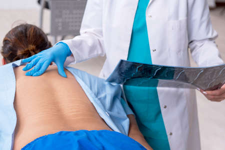 Young injured man visiting female doctor chiropractor