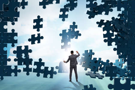 Businessman breaking the wall of jigsaw puzzle
