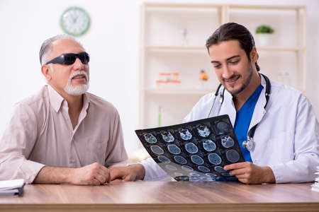 Old blind man visiting young male doctorの写真素材