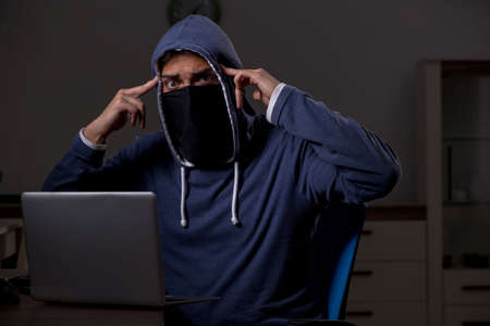 Male hacker hacking security firewall late in officeの写真素材