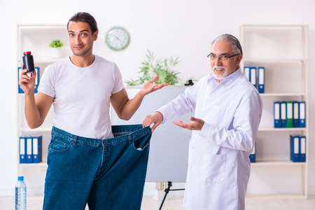 Doctor dietician and happy patient wearing large trousersの写真素材