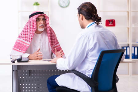 Old male arab visiting young male doctorの写真素材
