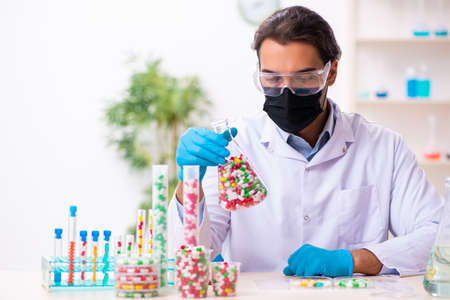 Young male chemist in drug synthesis concept