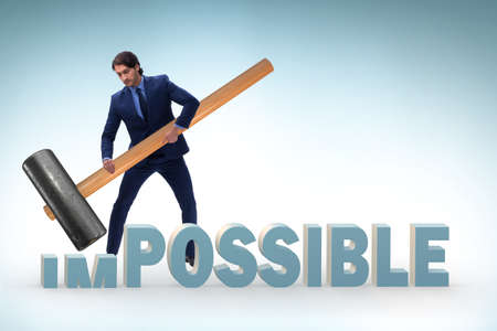 Businessman hitting the word impossible with hammer