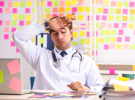 Male doctor with many conflicting priorititesの写真素材