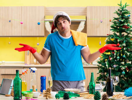Young man cleaning kitchen after Christmas partyの写真素材