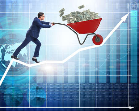 Businessman pushing wheelbarrow full of dollar moneyの写真素材