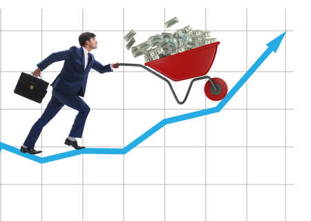 Businessman pushing wheelbarrow full of dollar moneyの写真素材