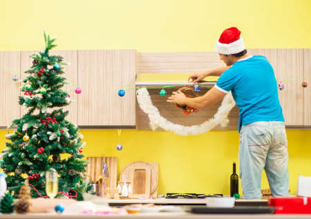 Young man celebrating Christmas in kitchenの写真素材