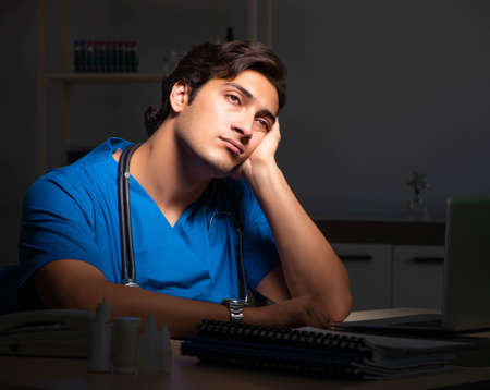 Young handsome doctor working night shift in hospitalの写真素材