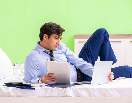 Businessman working overtime in hotel roomの写真素材