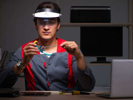 Young handsome repairman repairing computerの写真素材
