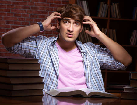 Young handsome student preparing for exams at nightの写真素材