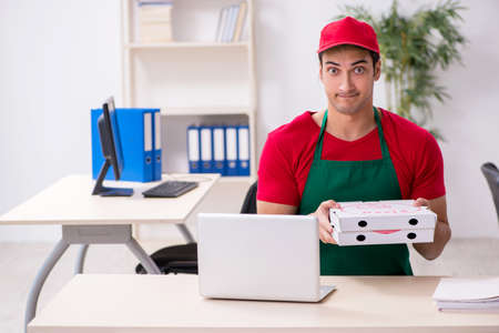 Young male pizza courier in industrial espionage conceptの写真素材