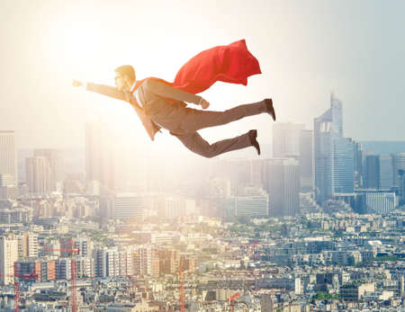 Superhero businessman flying over the cityの写真素材