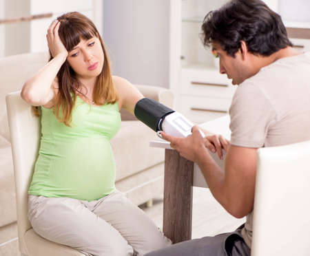 Husband checking pregnant wifes blood pressureの写真素材