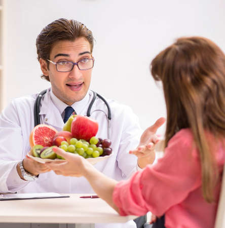 Pregnant woman visiting doctor discussing healthy dietの写真素材
