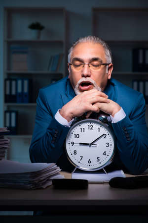 Old male employee working late in the officeの写真素材