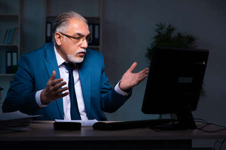 Old male employee working late in the officeの写真素材